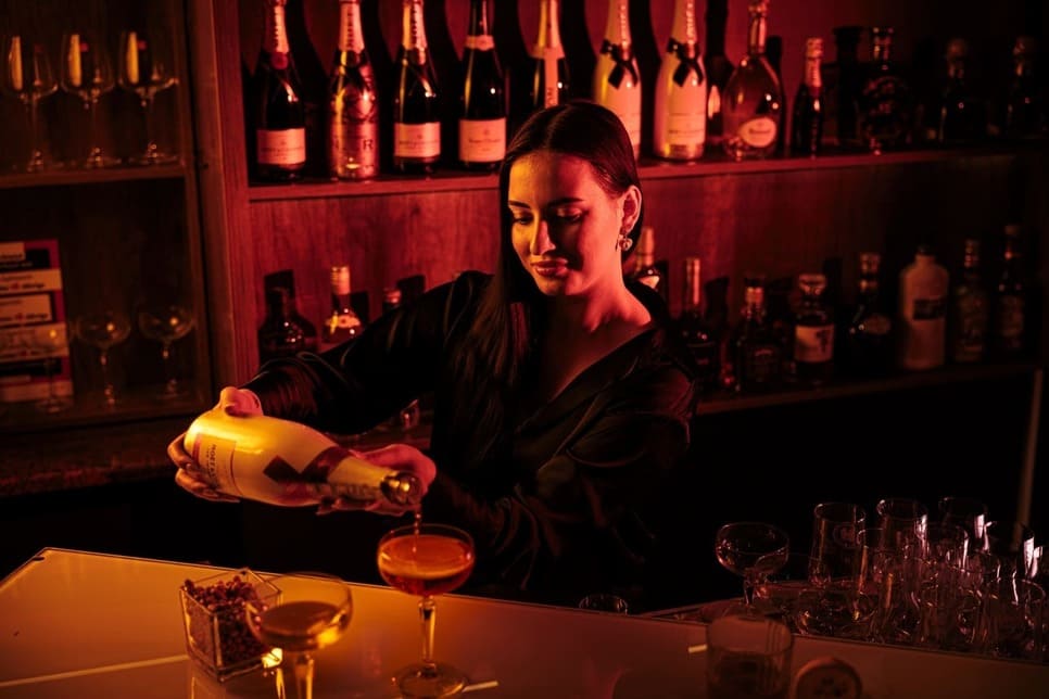 Barkeeperin schenkt zwei Gläser Champagner ein