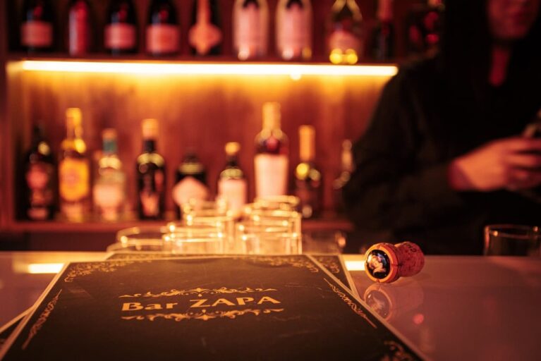Menükarte der Bar Zapa auf dem Tresen einer Bar neben einem Champagnerkorken