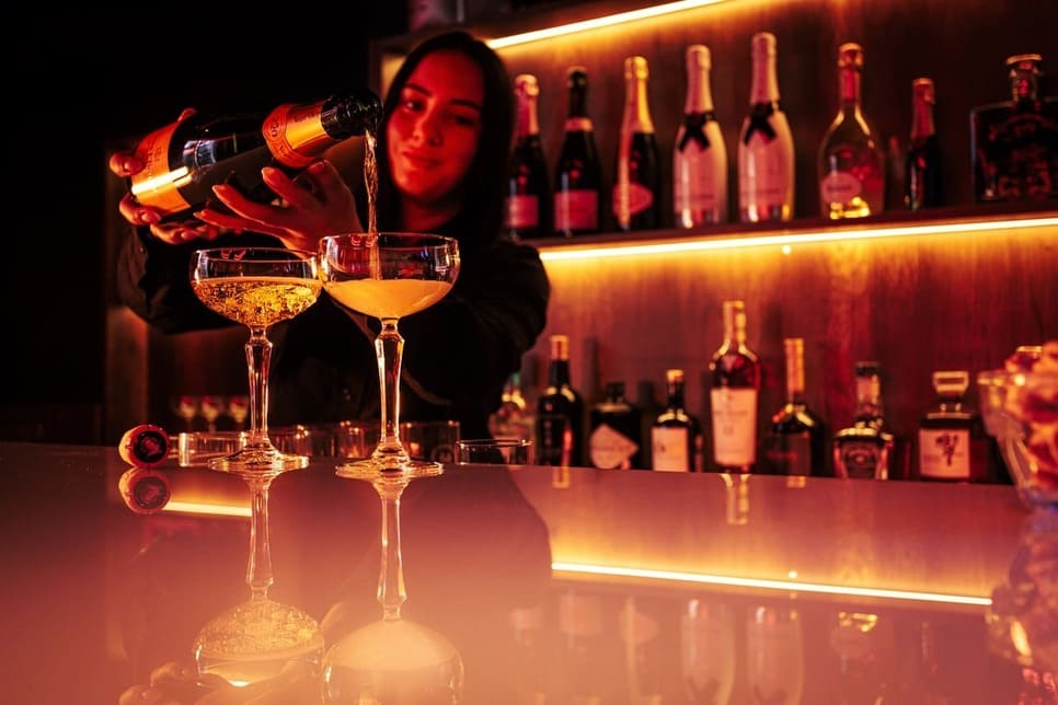 Barkeeperin schenkt zwei Gläser Champagner ein