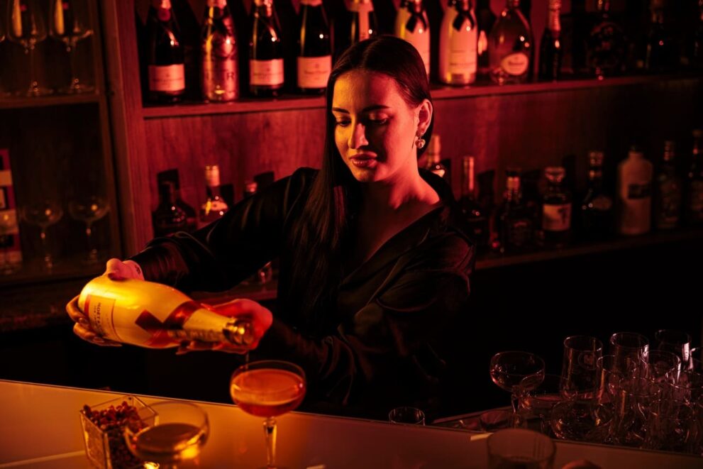 Barkeeperin schenkt Champagner aus in einem Gentlemans Club